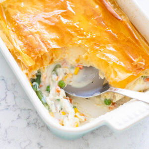 A baking dish with creamy chicken pot pie has phyllo dough on the top.