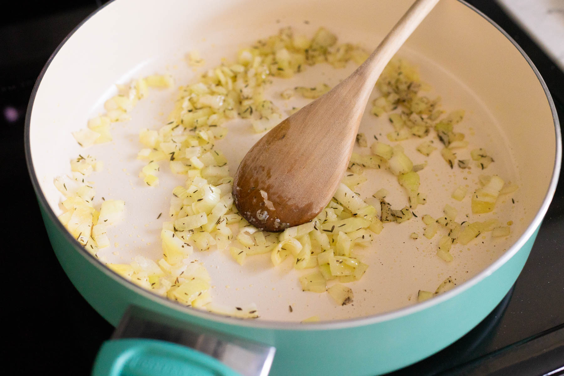 The chopped onion and thyme are cooking in olive oil in a large skillet.