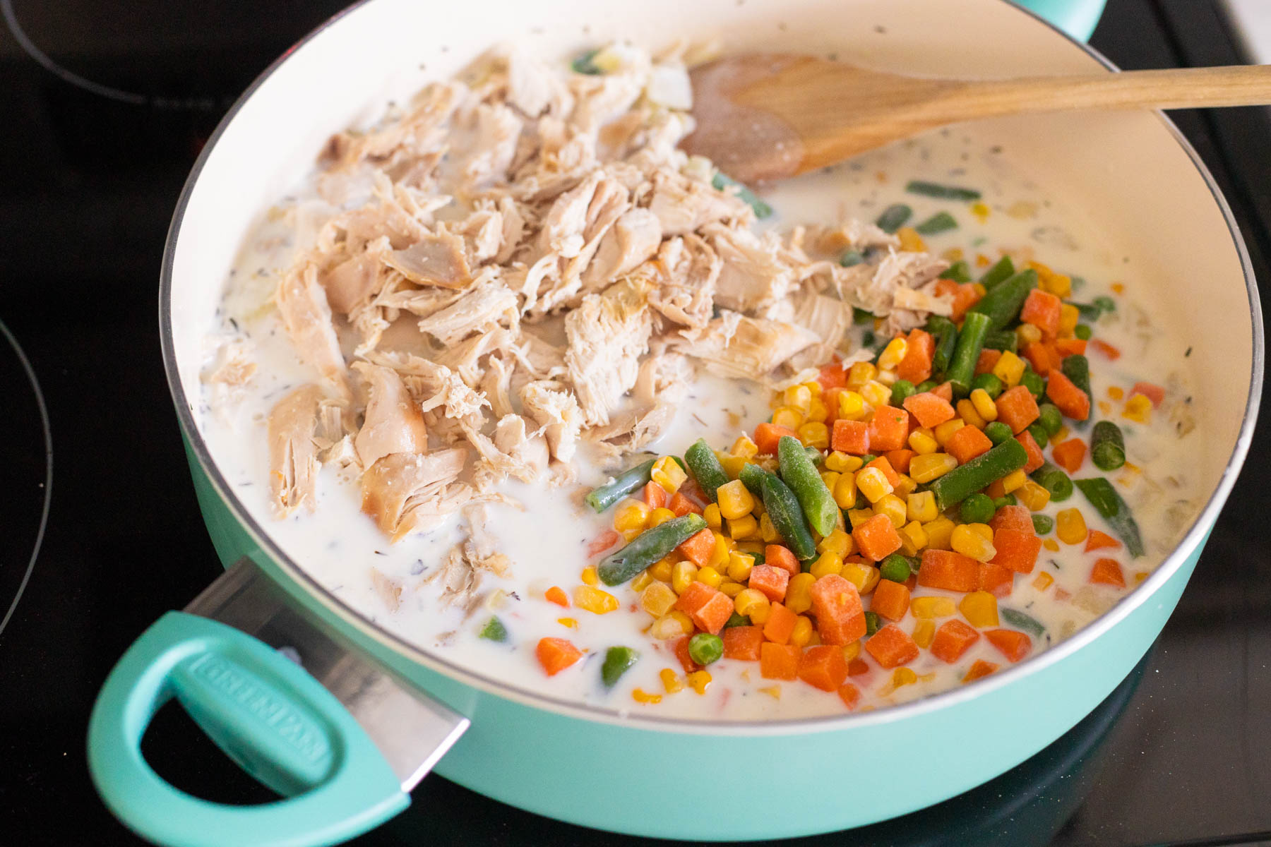 The shredded chicken and frozen vegetables are added to the skillet.