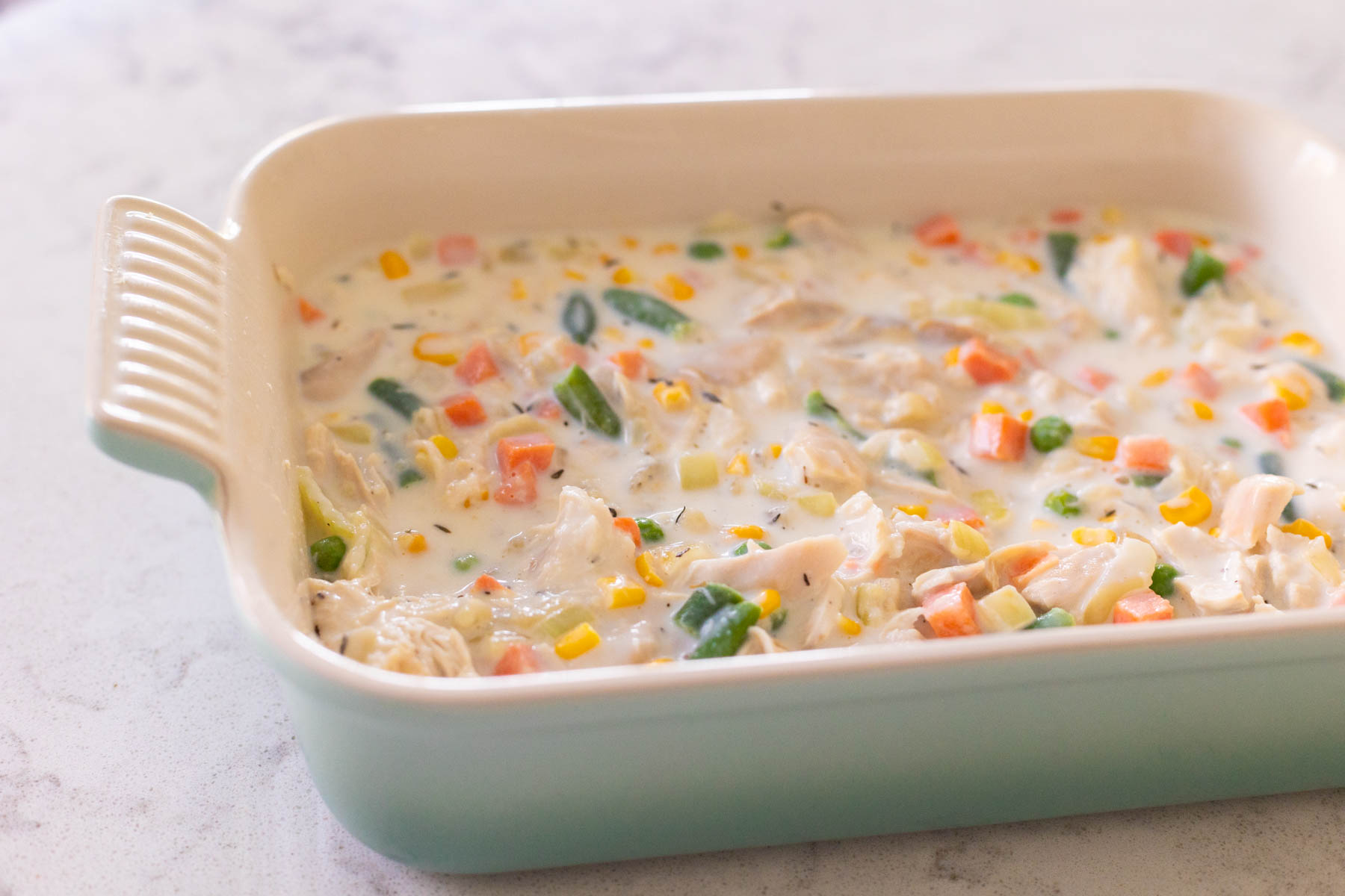 The baking dish is filled with the chicken pot pie filling.
