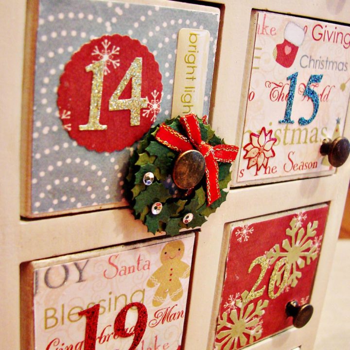 A wooden Advent calendar has been decorated with mod podge and craft paper.