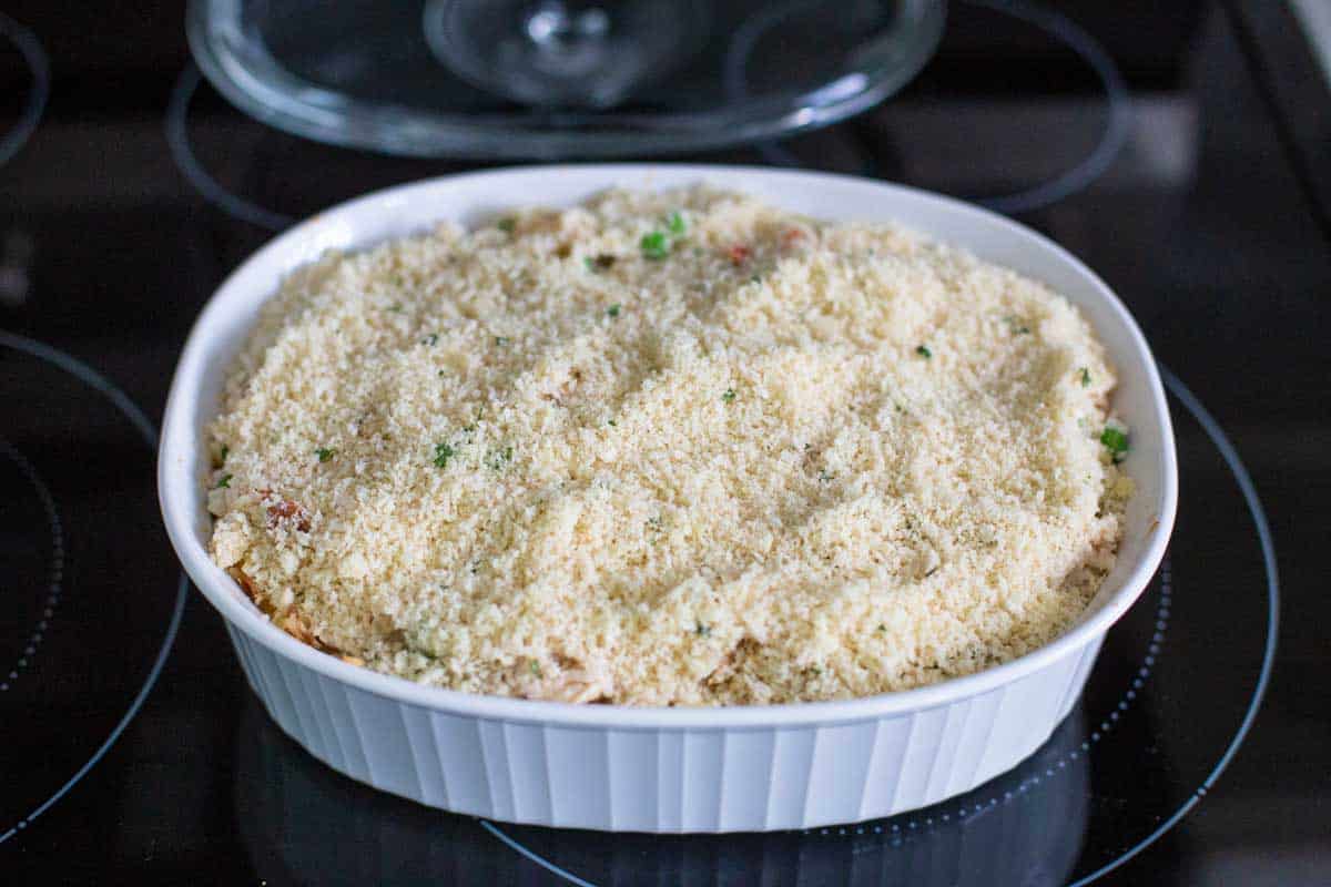 The chicken alfredo rice casserole sits on the stovetop and has had the breadcrumb topping sprinkled over the top to finish baking.