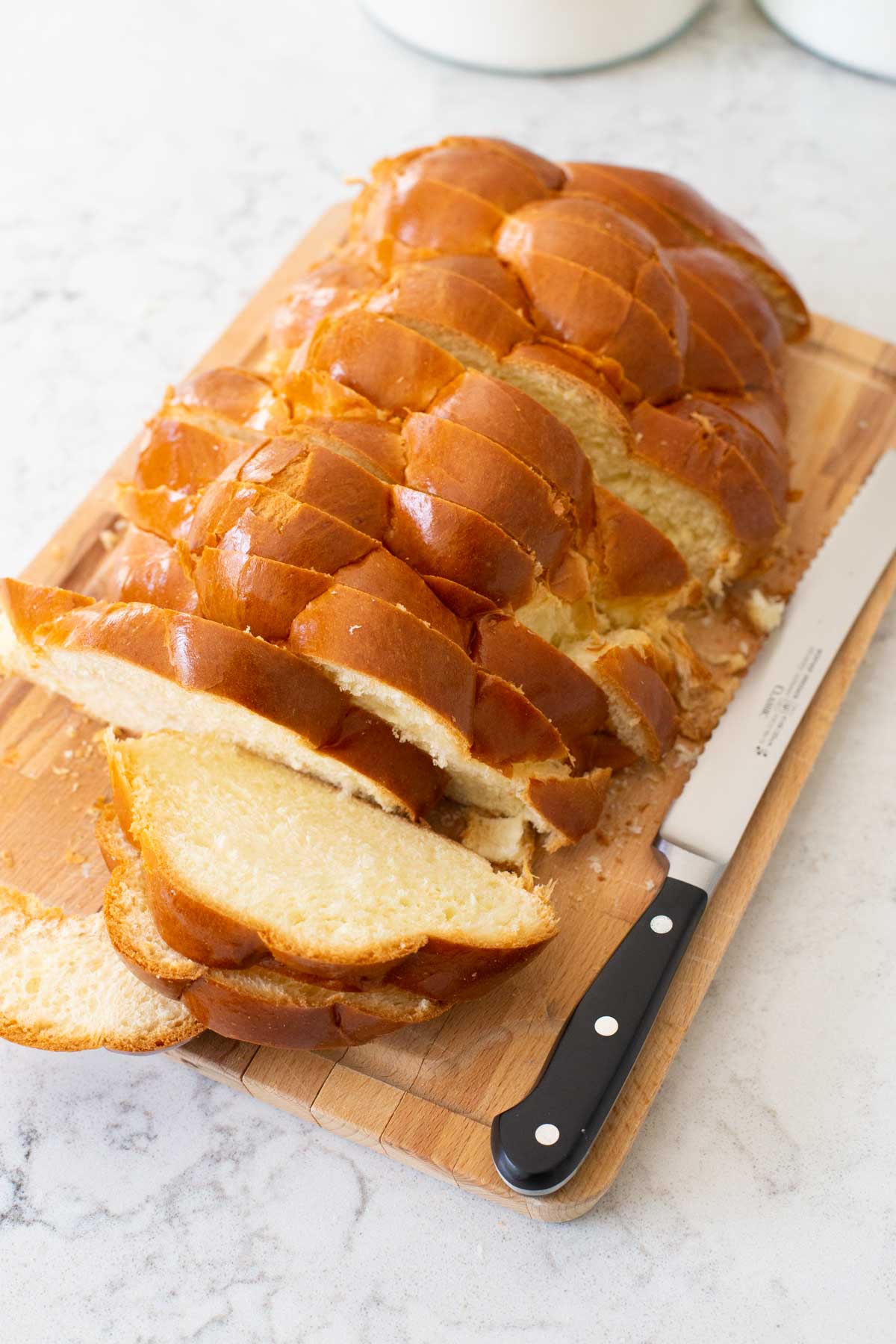A fresh loaf of challah bread has been sliced for making french toast.