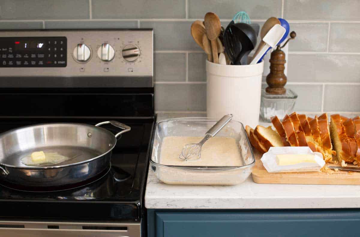 The scene shows the skillet on the left, the batter in the middle, and the sliced bread with a stick of butter on the right.