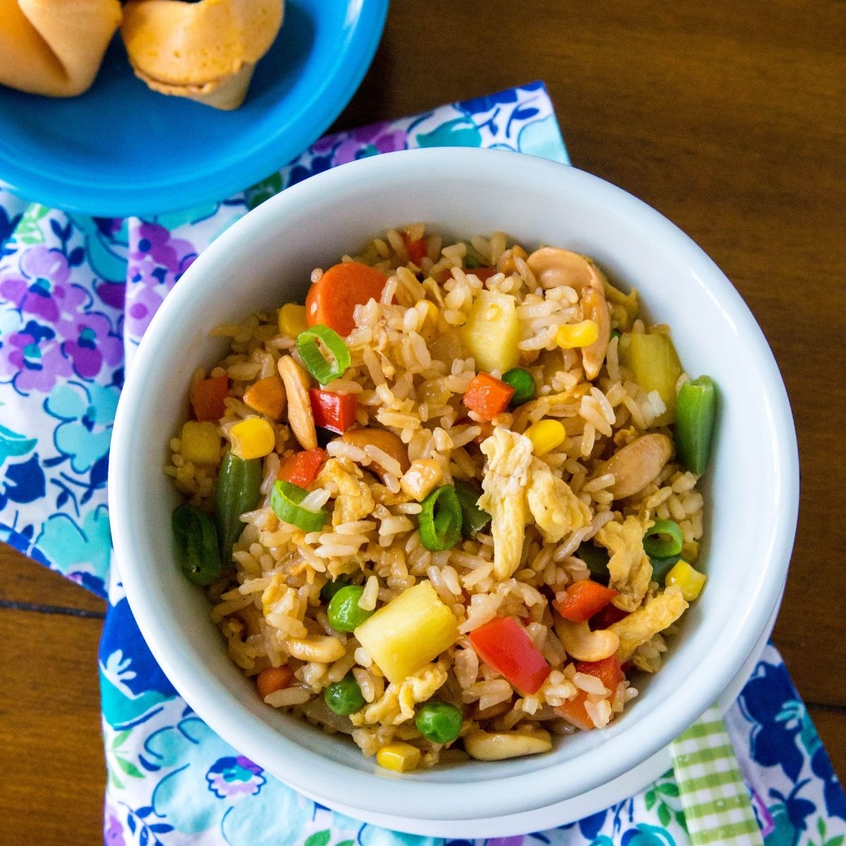 A bowl of chicken fried rice has fresh vegetables and chunks of chicken.
