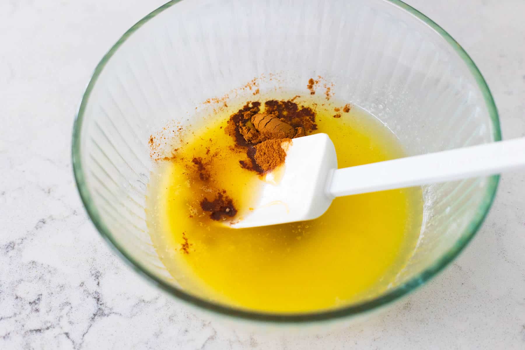 A mixing bowl filled with melted butter, honey, and cinnamon.