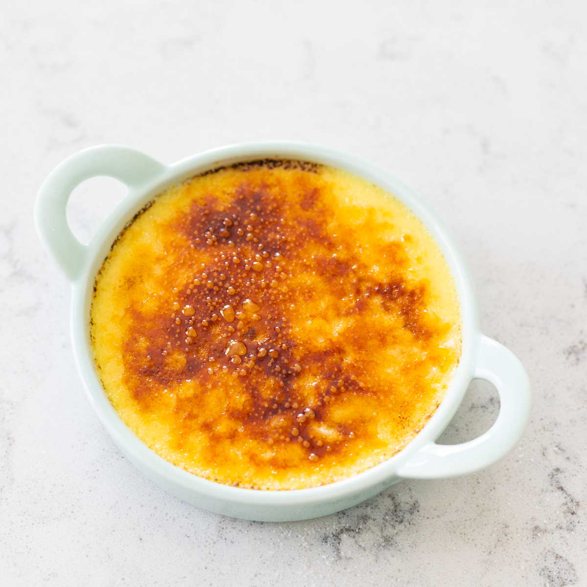The burned sugar topping on a ramekin shows how dark to torch the sugar.
