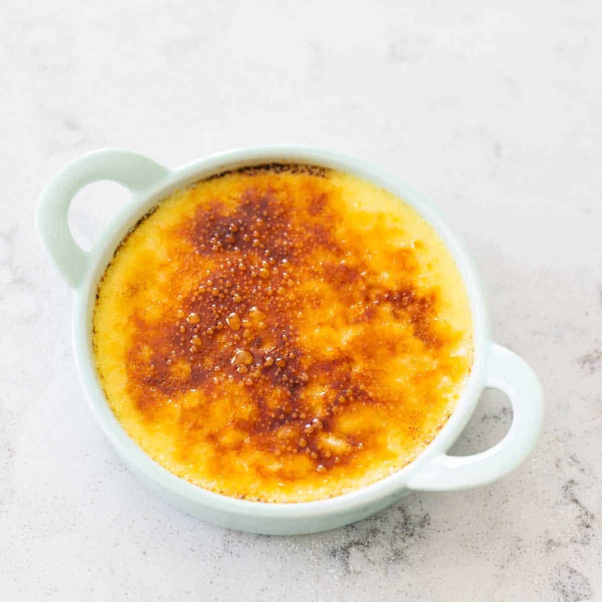 The burned sugar topping on a ramekin shows how dark to torch the sugar.