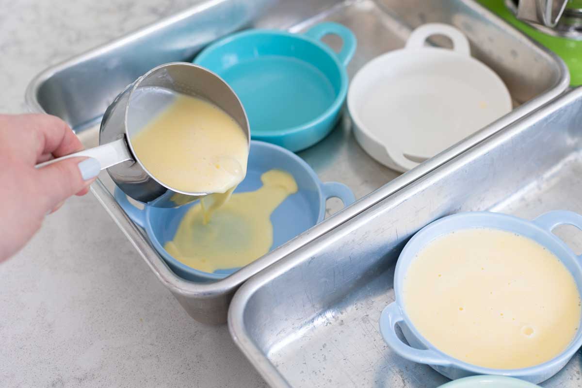 The custard is being poured into each ramekin with a measuring cup.