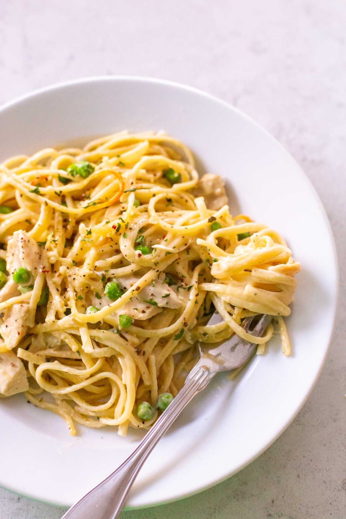 A plate of pasta has a fork twirling the next bite of tetrazzini.