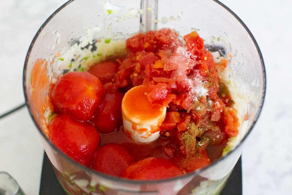 The whole tomatoes, diced tomatoes, and seasonings have been added to the food processor.