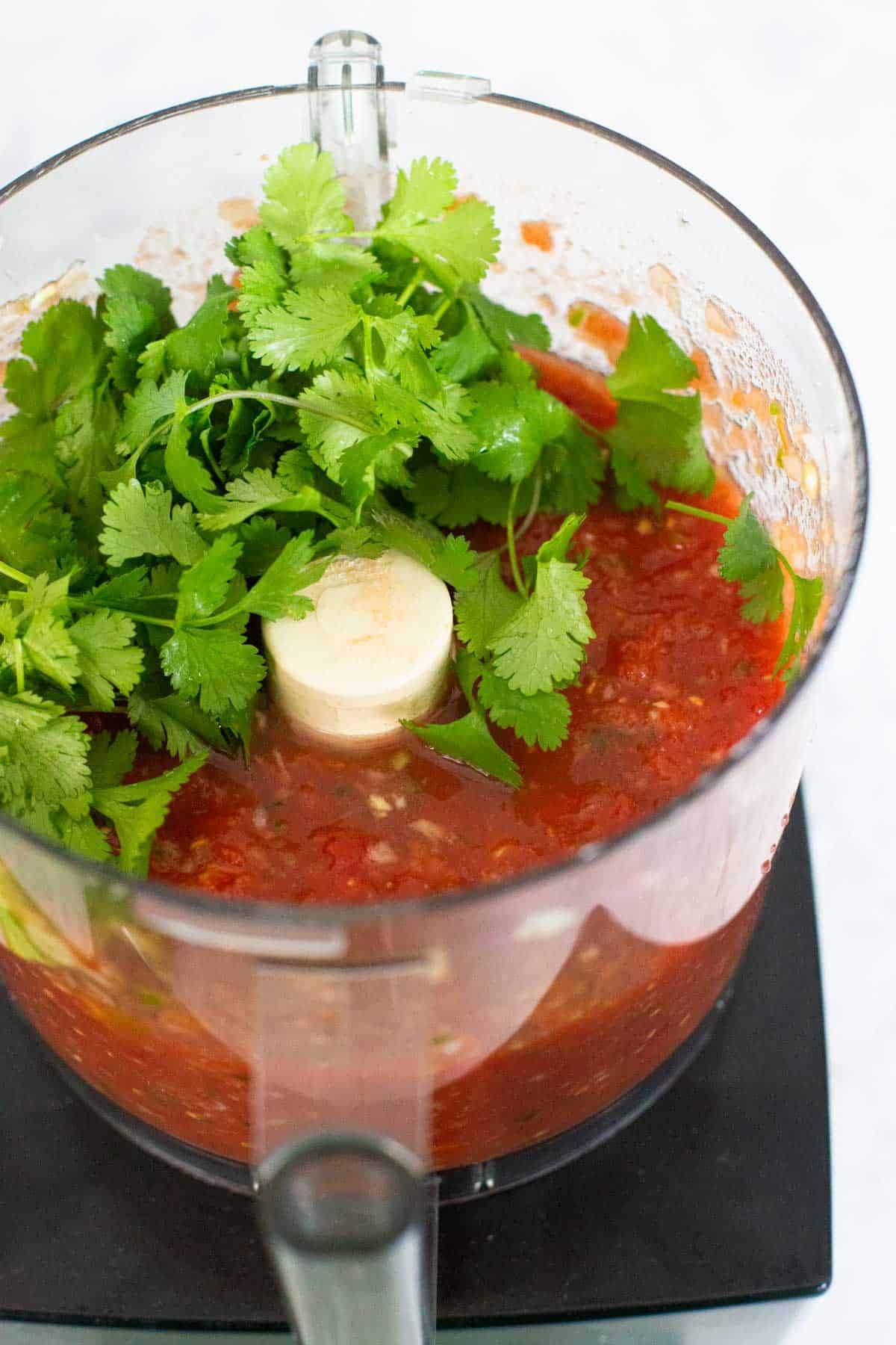 The tomatoes have been chopped and now fresh cilantro is on top of the mixture.