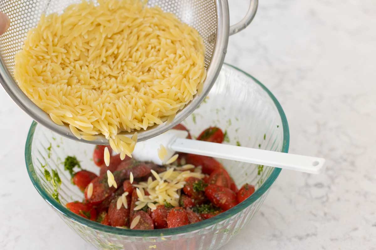 The cooked orzo is added to the tomato bowl.