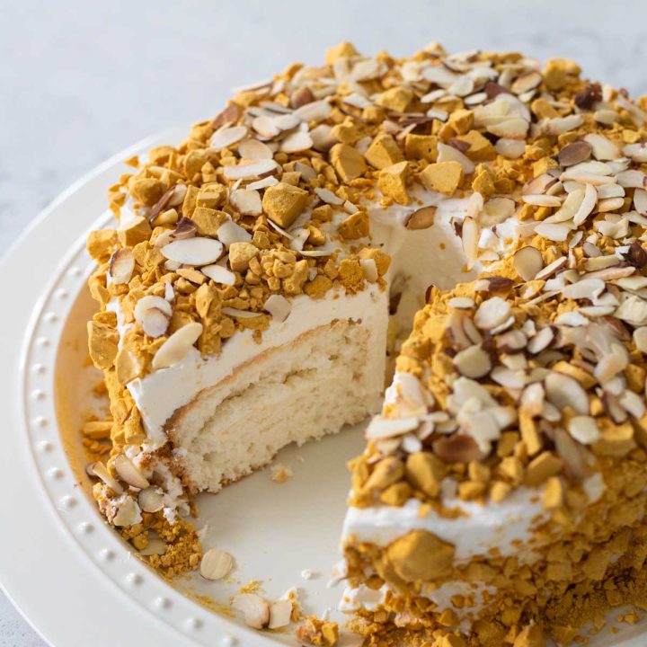 The almond crunch cake has candy crunchies and almonds on top. A slice is missing so you can see the light and airy sponge cake underneath.