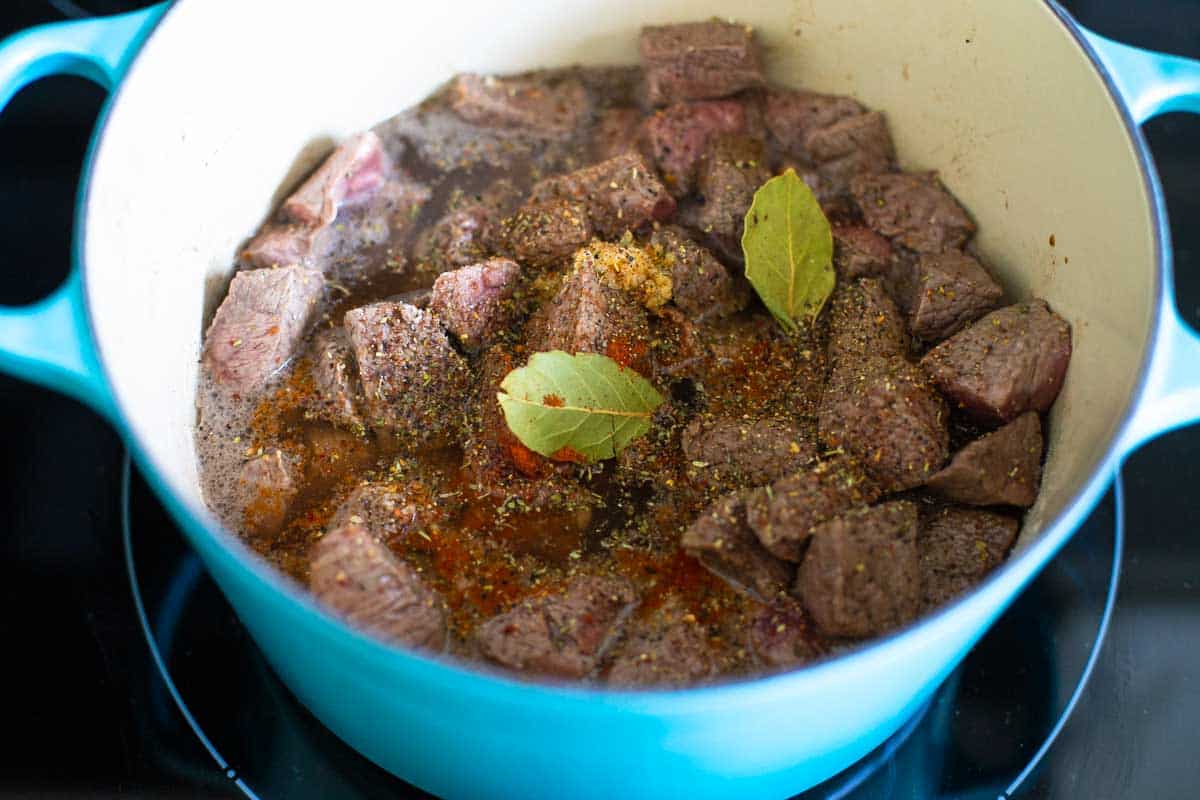 The spices and bay leaves have been added to the stew pot.