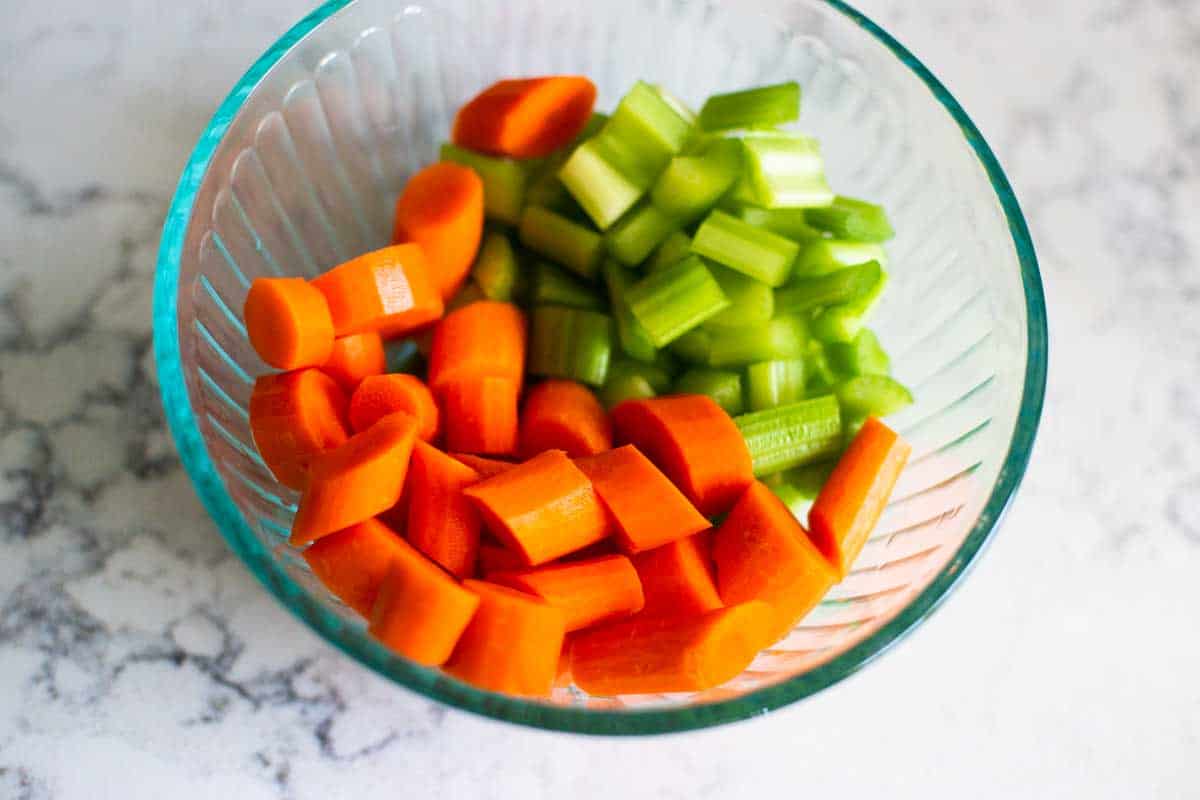 The chopped carrots and celery are in a bowl next to the stove top.