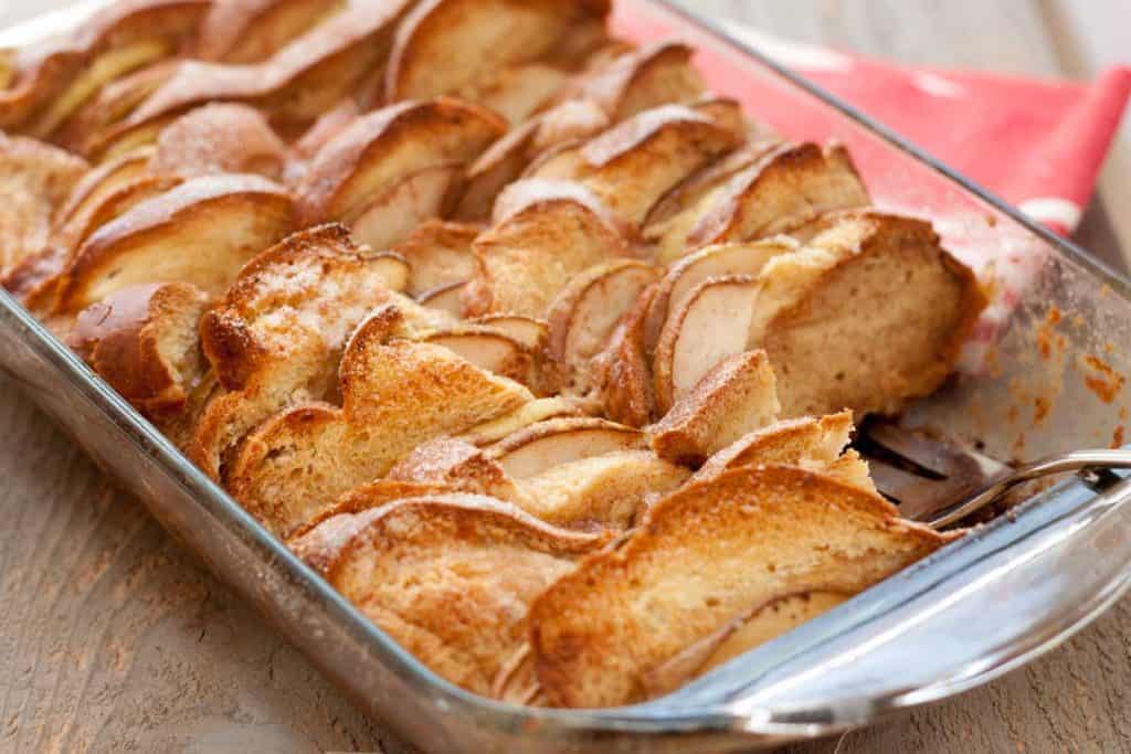 The full casserole pan of homemade bread pudding with pears and chocolate. The tops of each slice of bread are toasted a golden brown.