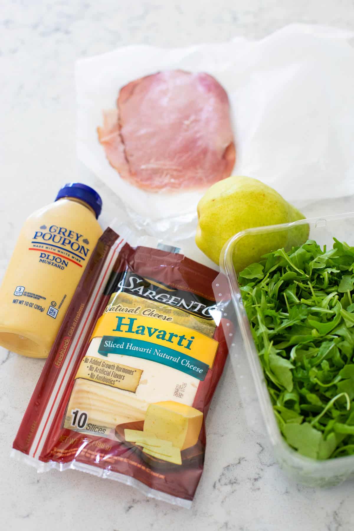 The ingredients to make ham and havarti sandwiches ar eon the counter.