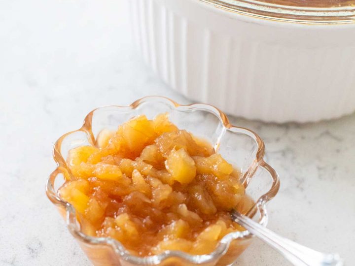 A serving of applesauce with a spoon.