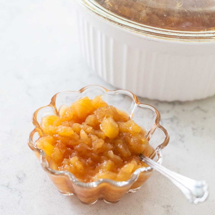 A serving of applesauce with a spoon.