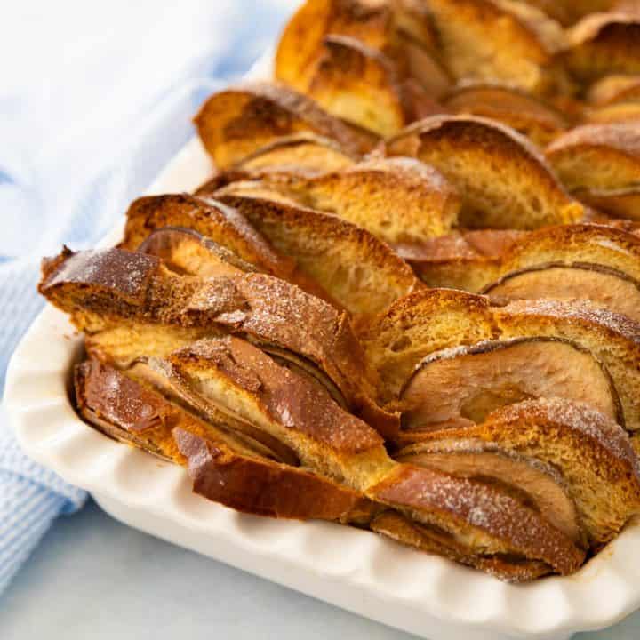 The baked pear bread pudding is in a white baking dish next to a blue napkin.