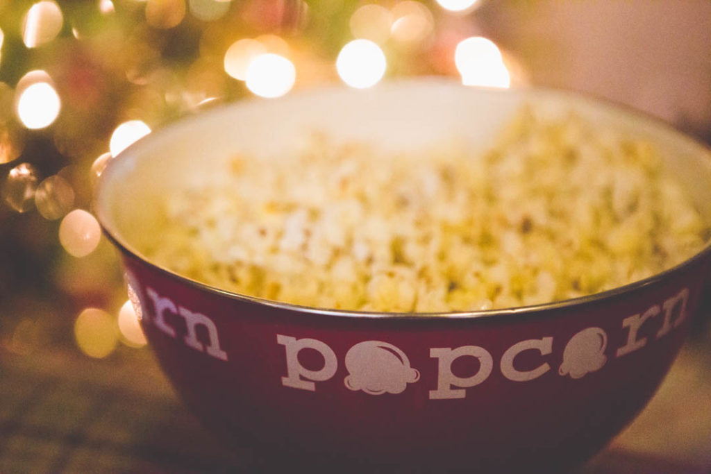 A large red bowl of popcorn is waiting for a Christmas movie.
