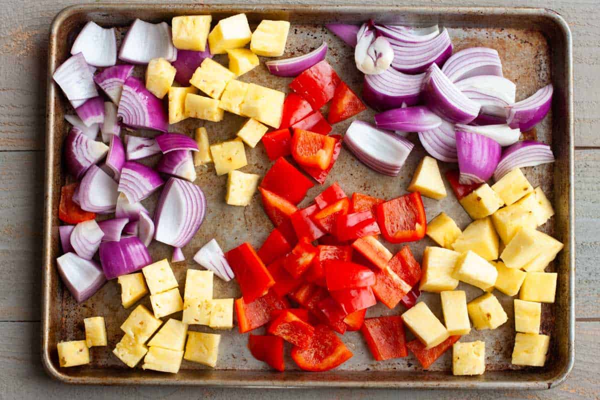 The chopped vegetables and fruit are on a large roasting sheet.