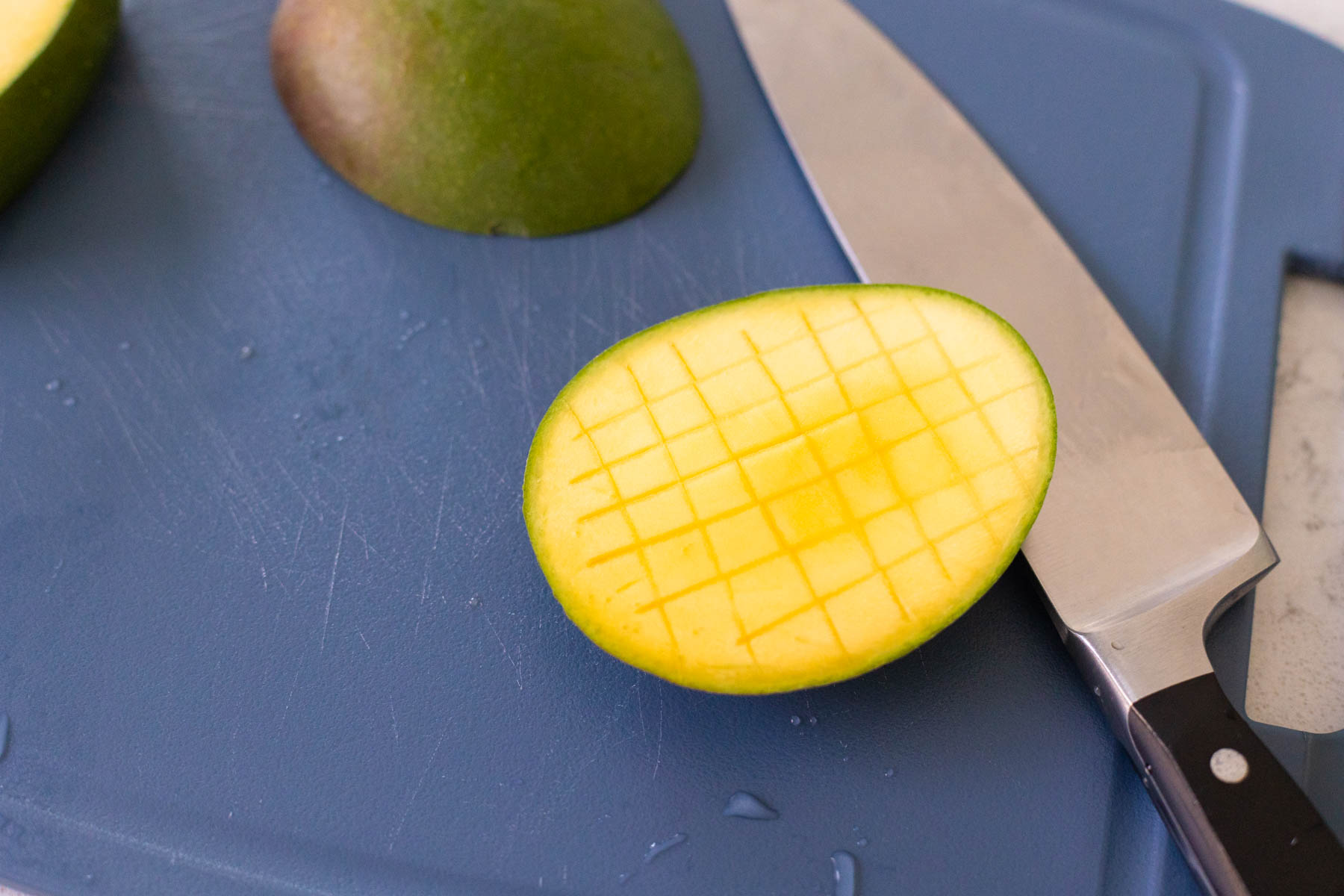 The fresh mango has been scored into a grid with the knife.