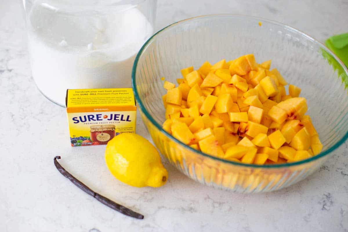 The ingredients for homemade peach freezer jam are on the kitchen counter.