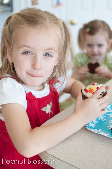 A young girl eats chocolate peppermint bark cookies with her sister.