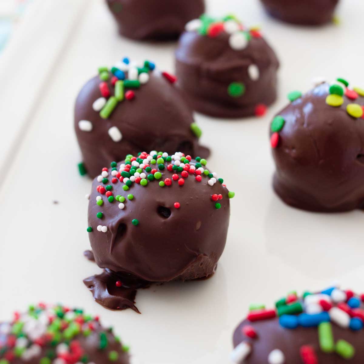 A tray of chocolate covered Oreo truffles with red and green sprinkles.