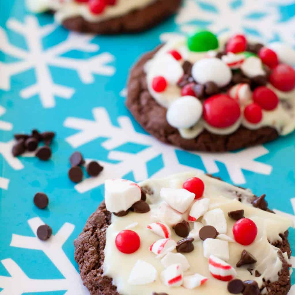 A blue platter with chocolate peppermint barks decorated in crushed candy canes and M&Ms.