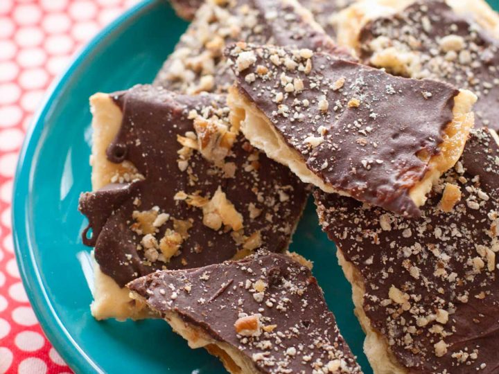 A plate with several pieces of cracked saltine cracker toffee with chocolate coating.