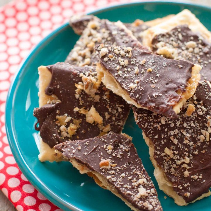 A plate with several pieces of cracked saltine cracker toffee with chocolate coating.