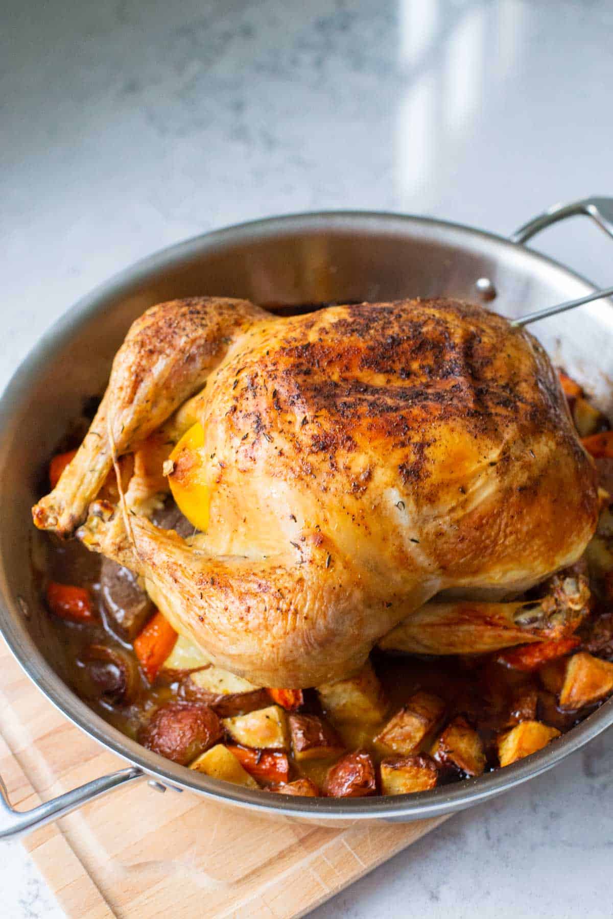 The finished roast chicken on a bed of vegetables in the roasting pan.