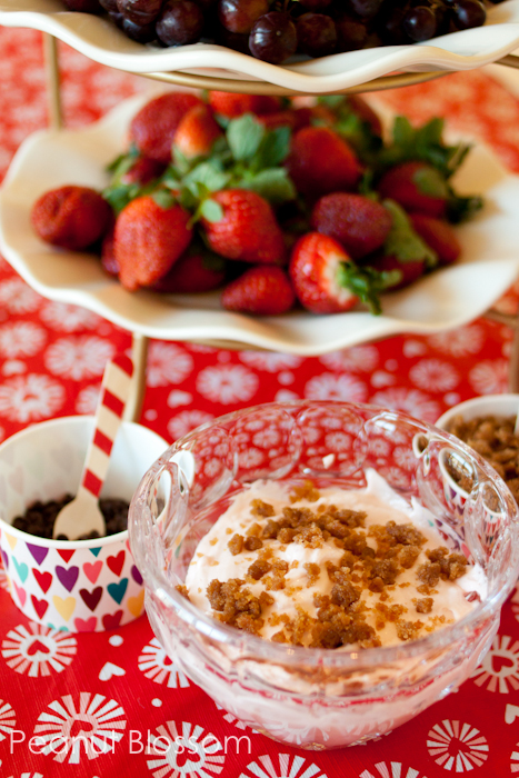 A platter of fresh strawberries next to a bowl of strawberry cheesecake dip.