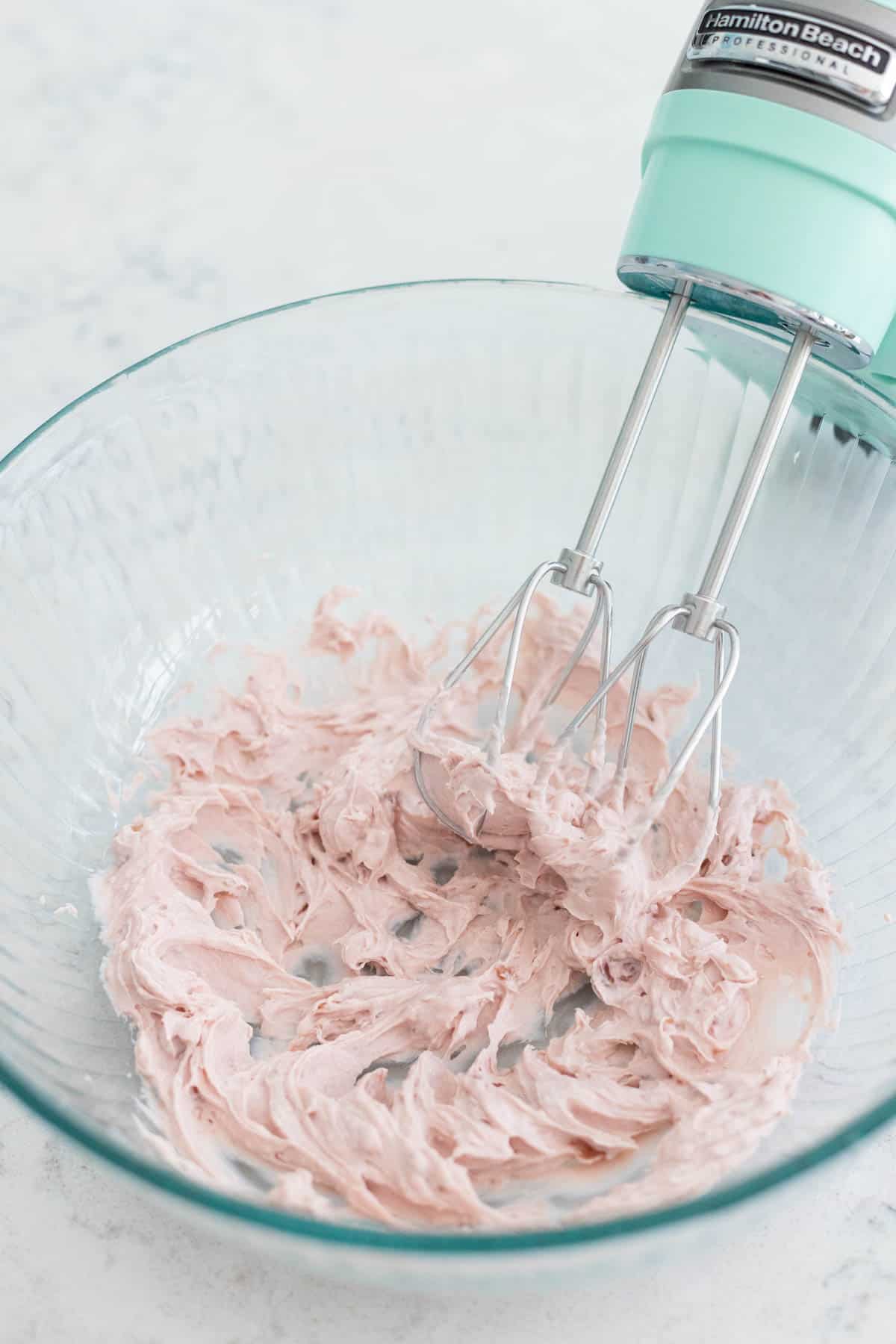 The strawberry cream cheese has been whipped by a hand mixer.