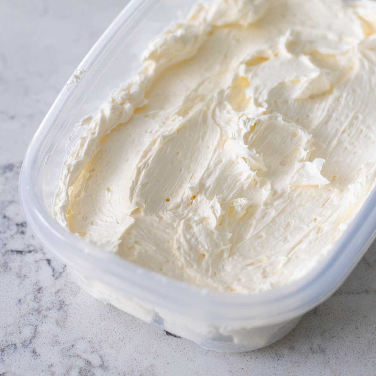 The Swiss meringue buttercream frosting has been smoothed into a freezer-safe container for storage.