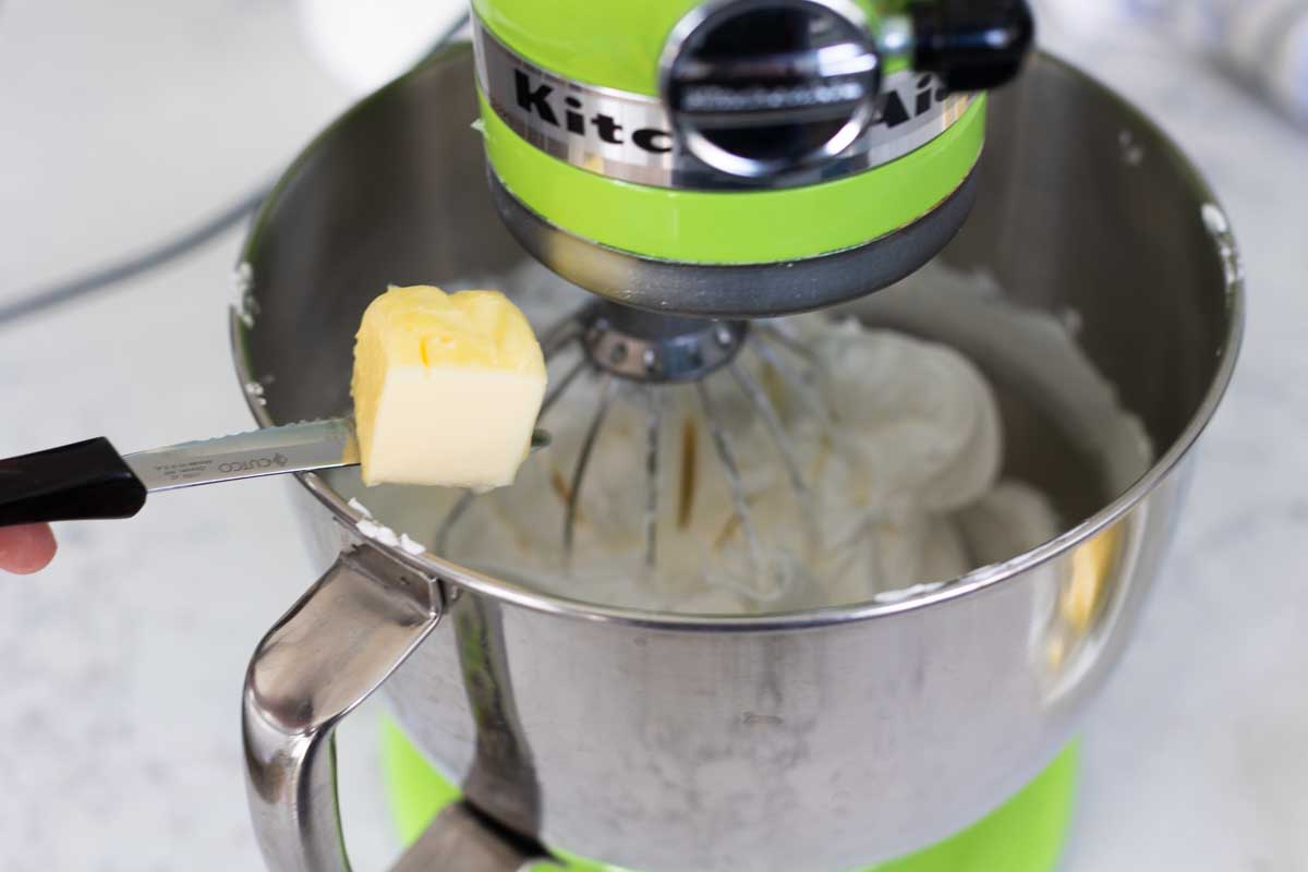 Softened butter is added to the meringue in a chunk of 2 tablespoons at one time.