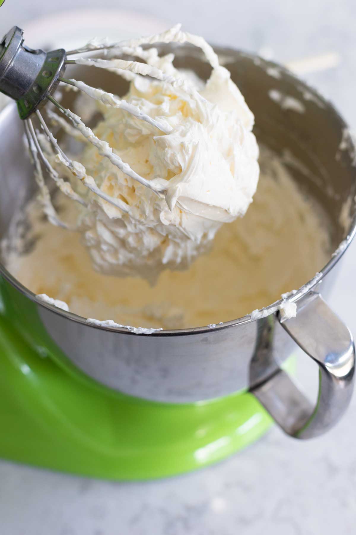 The frosting is clinging to the mixer whisk.