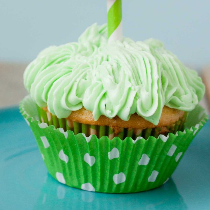 A green frosted cupcake with a white polka dot wrapper.