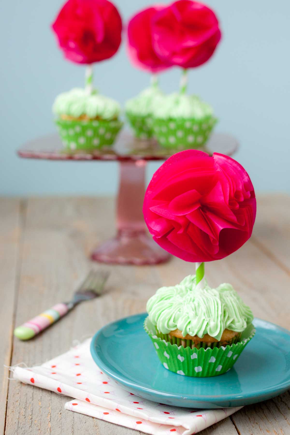 The Swiss meringue buttercream has been used on a batch of cupcakes with hot pink flower toppers.