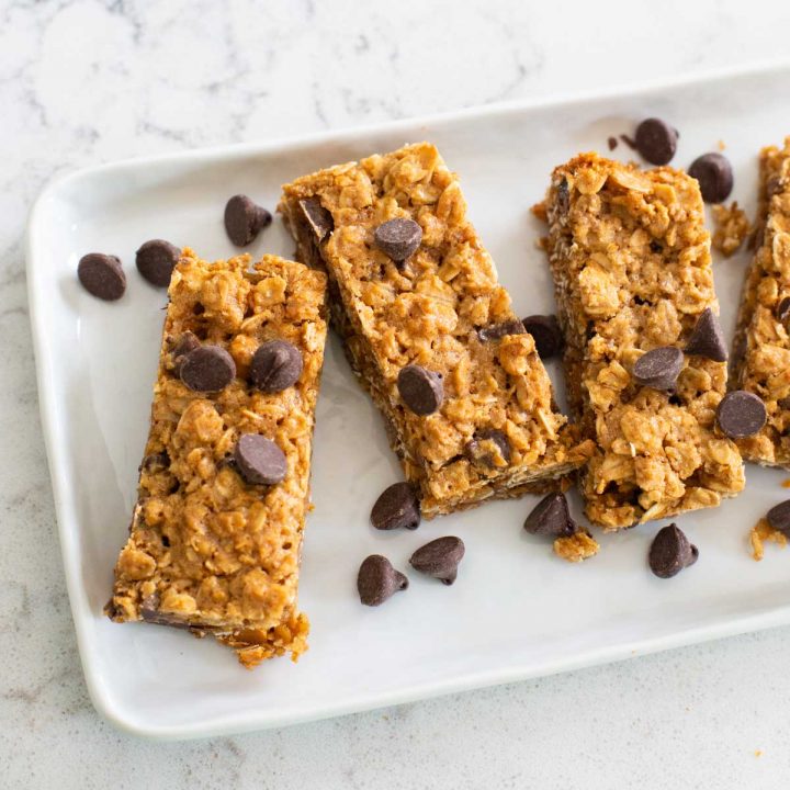 A platter of homemade granola bars has chocolate chips sprinkled over the top.