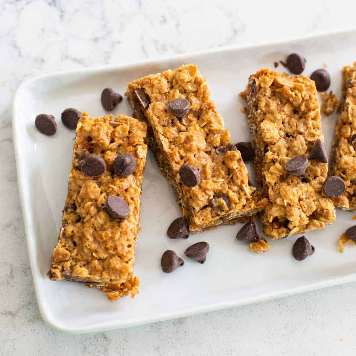 A platter of homemade granola bars has chocolate chips sprinkled over the top.