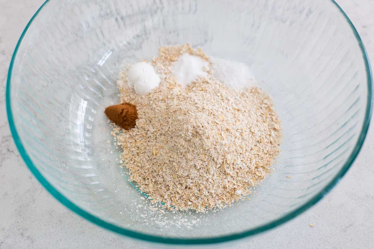 The oat flour, baking powder, and baking soda, and cinnamon are in a mixing bowl.
