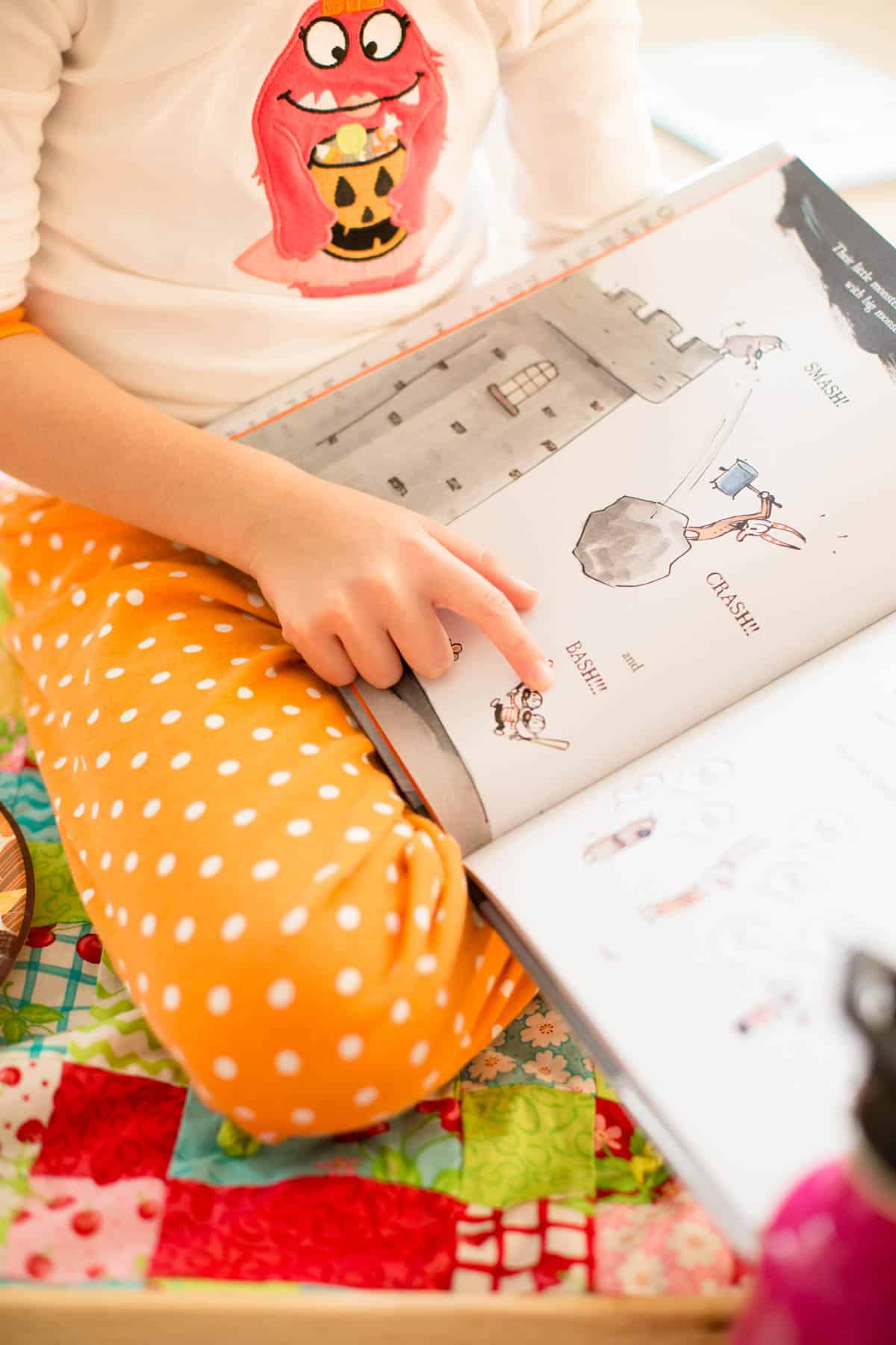 A young girl points to the story she is reading out loud for the reading picnic.