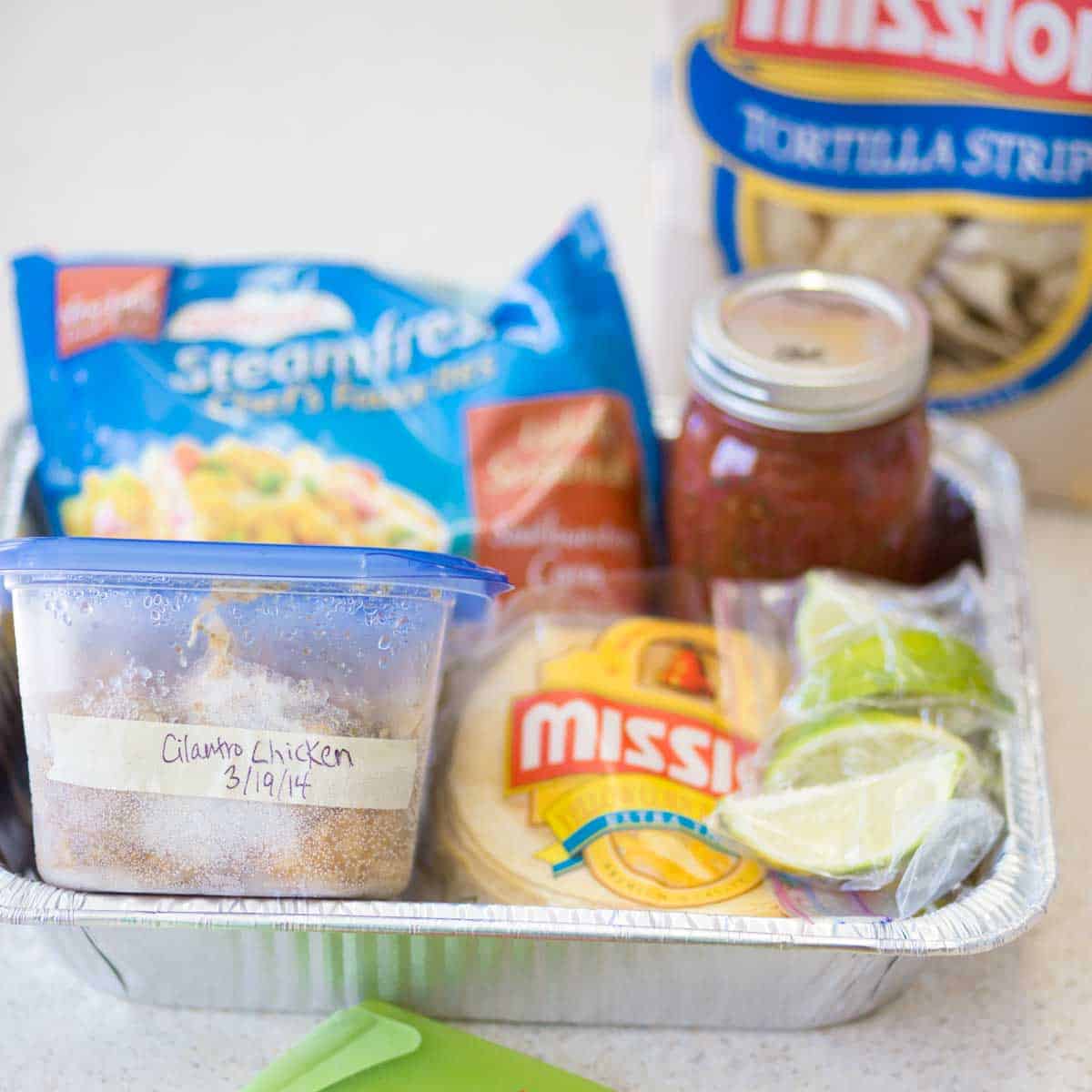 A meal train dinner kit featuring supplies for tacos sits in an aluminum tray for easy delivery.