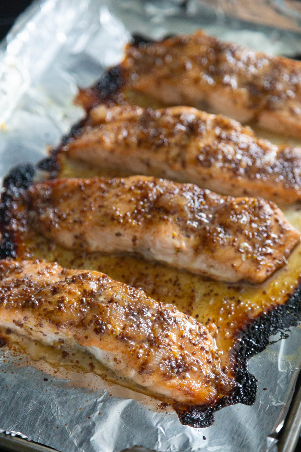 The broiled salmon is ready to be served. It is coated in a thick glaze with mustard seeds.
