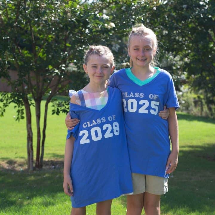 Two young girls wearing high school graduation t-shirts for a milestone photo.