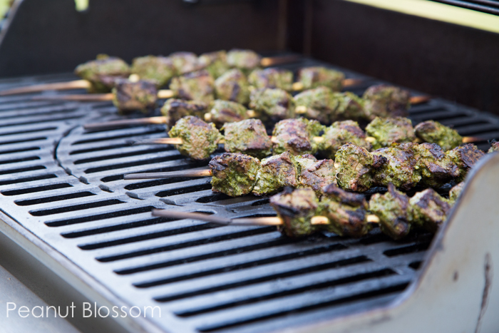 A grill has steak kabobs cooking on the grate.